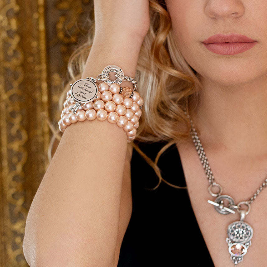 Woman wearing a pearl bracelet and silver necklace with a decorative background