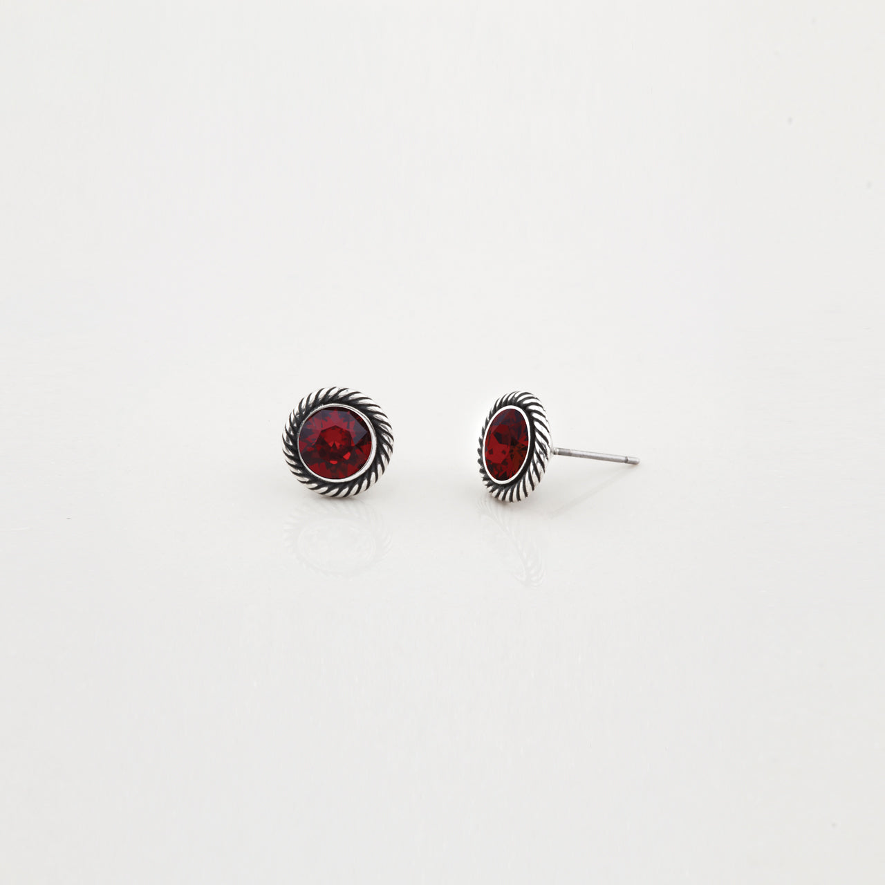 Pair of silver earrings with red gemstones on a white background