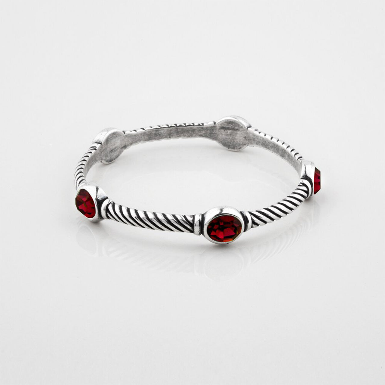 Silver bracelet with red gemstones on a white background