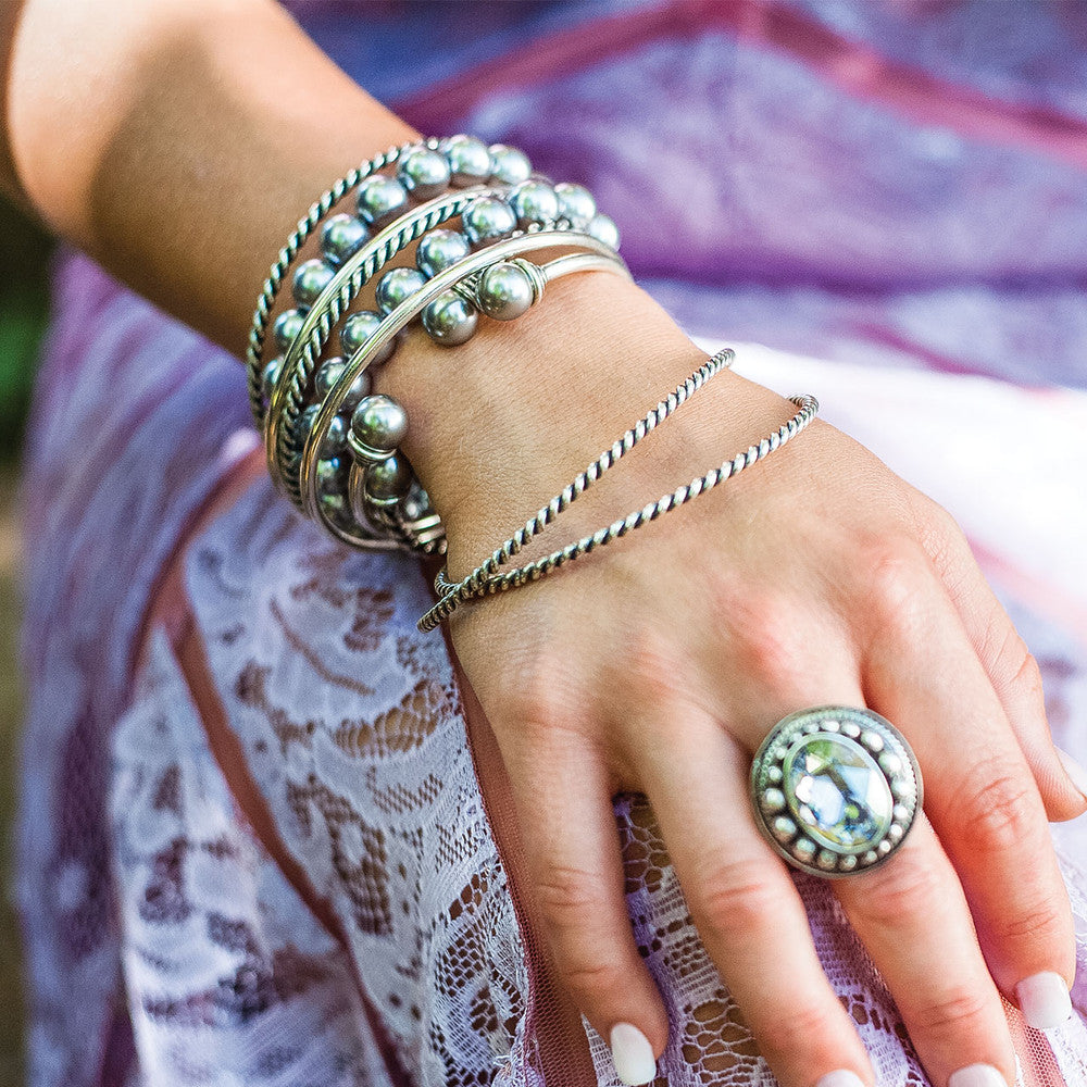 Close-up of a hand wearing Miglio silver bracelets and a ring.