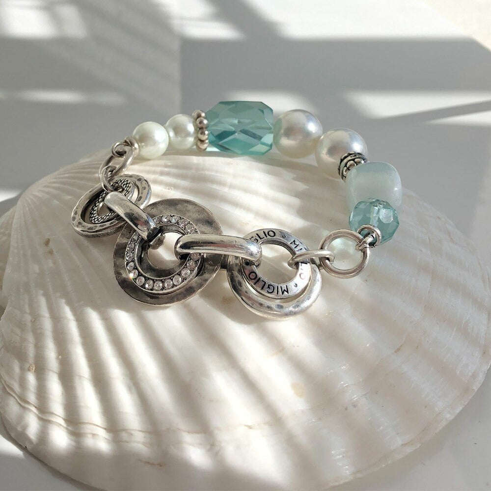Silver chain bracelet with turquoise and pearl beads on a shell