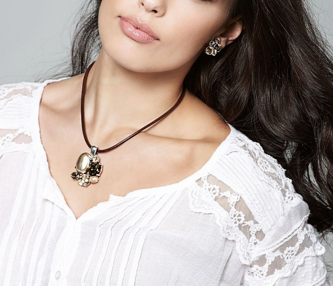 Woman wearing a white lace top and a necklace with a Crystal brown Cluster Pendant on a gray background