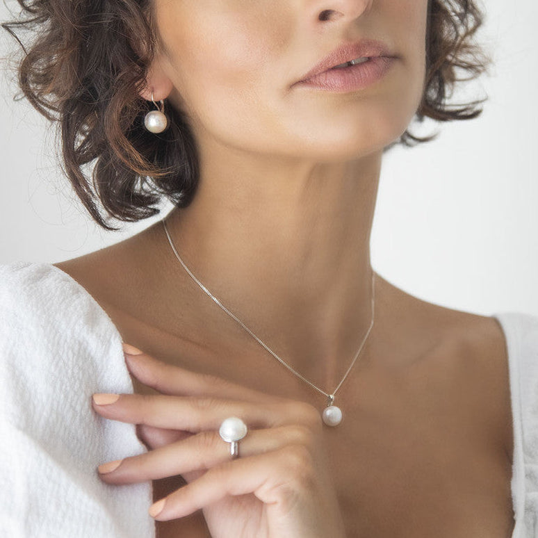 Woman wearing a pearl necklace and Miglio Urban Zen Pearl Ring