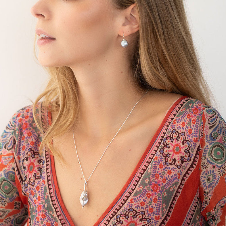Woman wearing a necklace and earrings against a plain background
