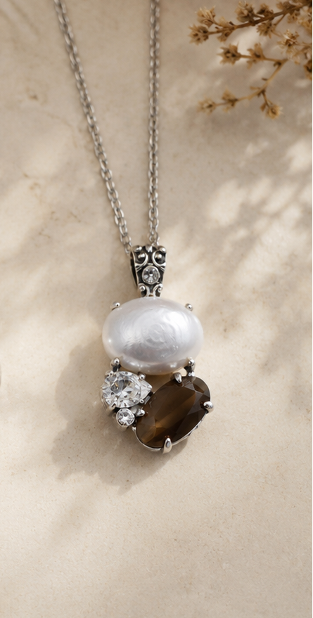 Necklace with a pendant featuring pearls, a diamond, and a brown stone on a beige background.