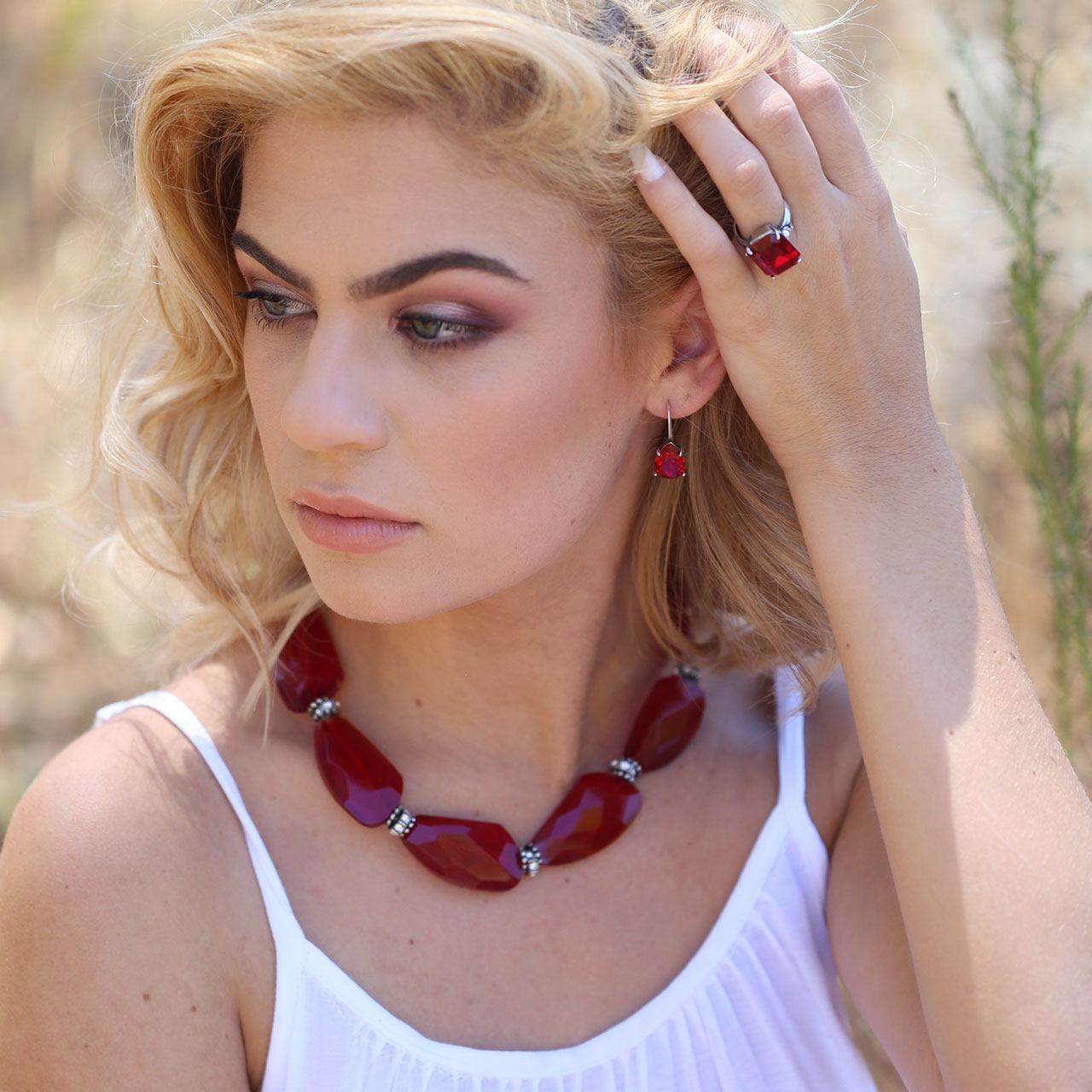 Woman wearing a red ring, necklace and earrings outdoors