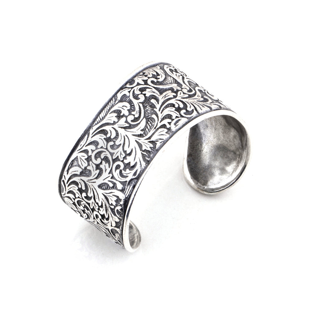Silver cuff bracelet with intricate patterns on a white background