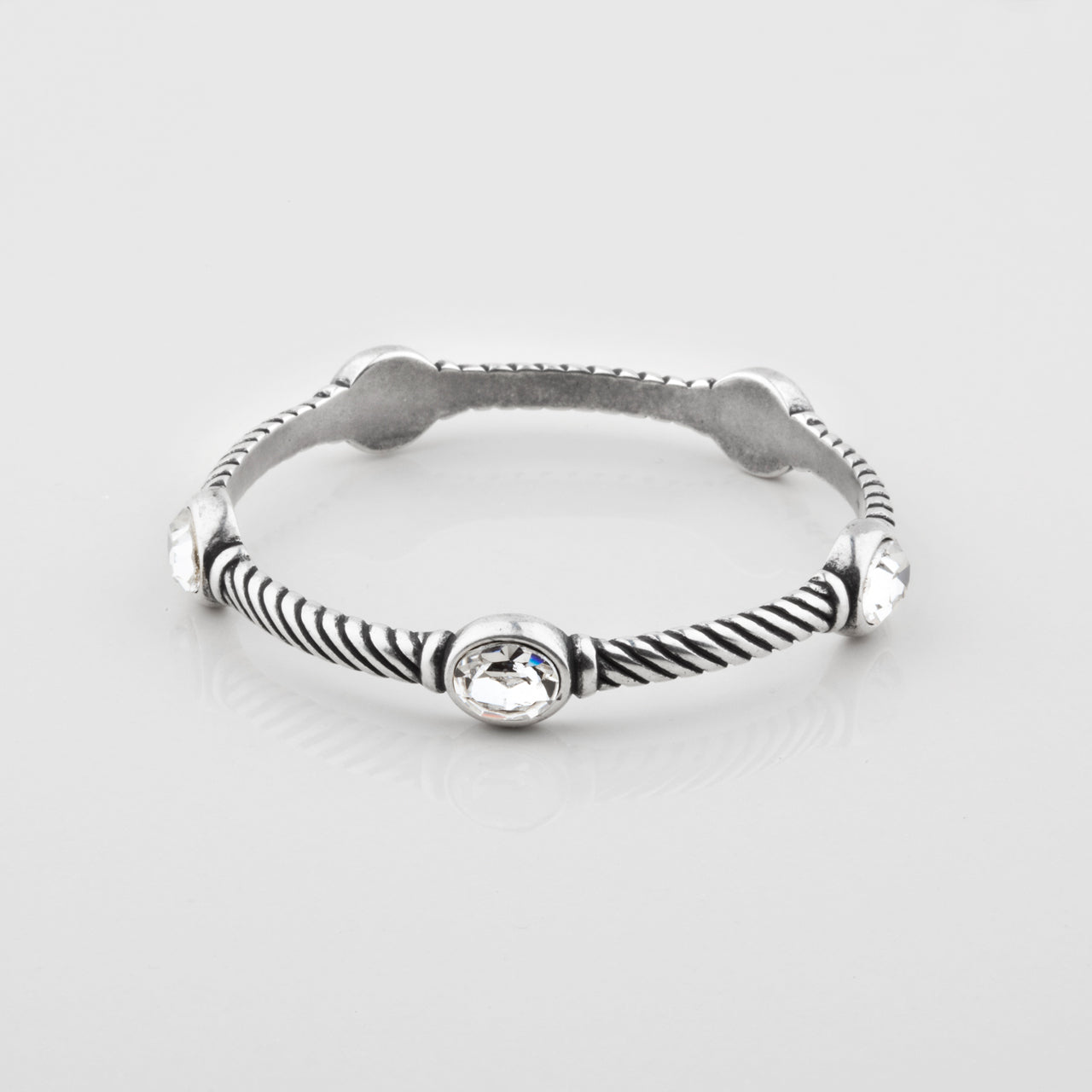 A burnished silver bangle bracelet featuring a twisted rope pattern, with five bezel-set clear crystal.