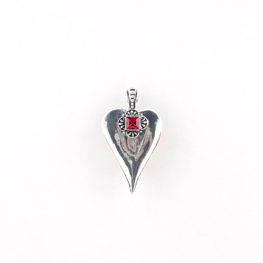 A silver plated heart-shaped pendant with a red Swarovski crystal embellishment at the top center, displayed against a white background.